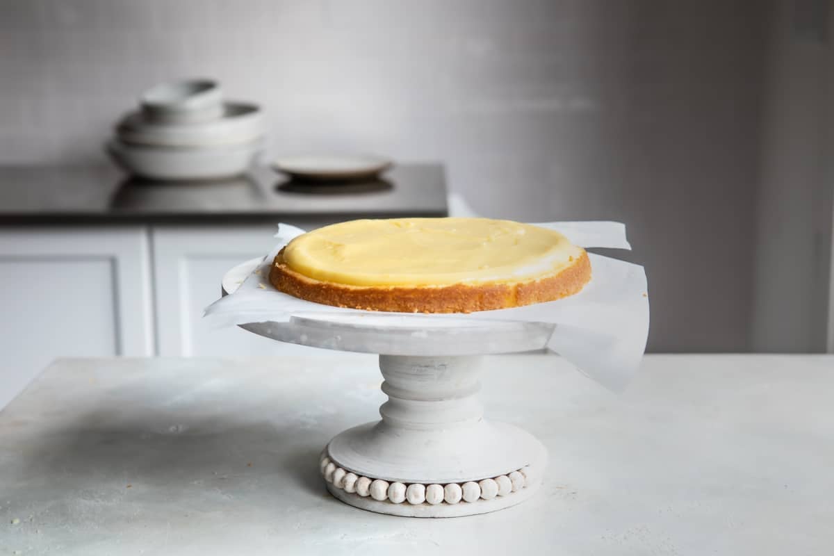 A layer of vanilla cake set on a cake stand with pastry cream spread over it.