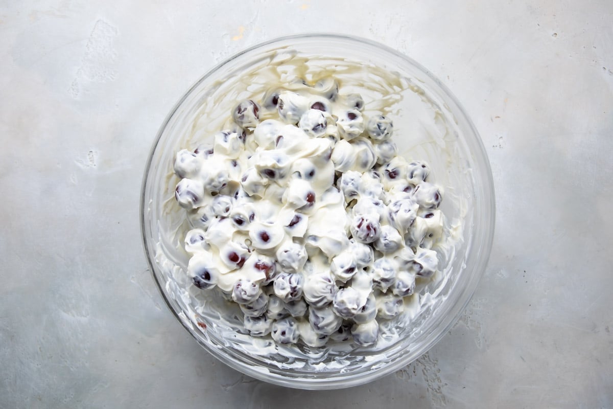 A large serving bowl full of grape salad without the sugar and nut topping.
