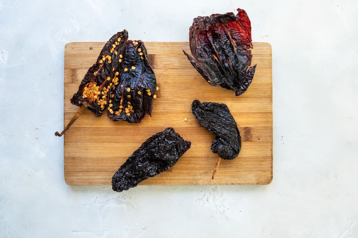Opening dried ancho chiles to remove the stem and seeds.