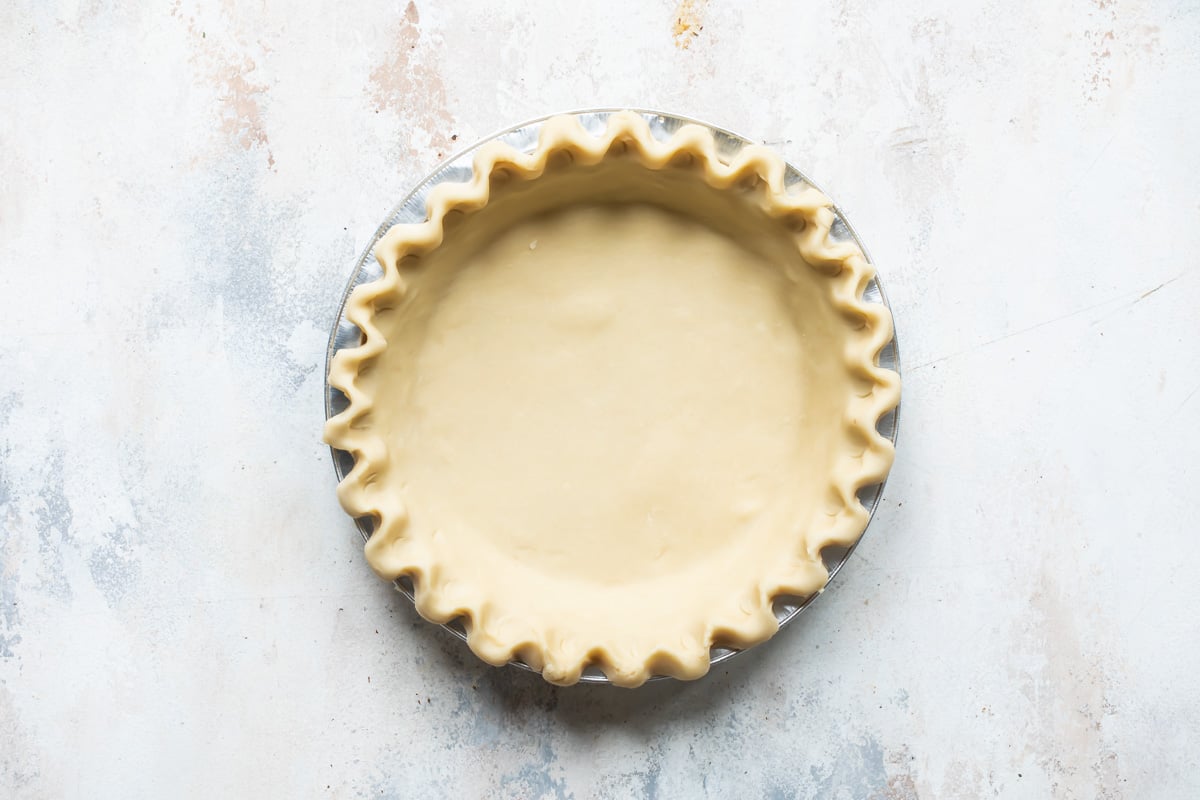 An unbaked pie crust with a fluted edge.