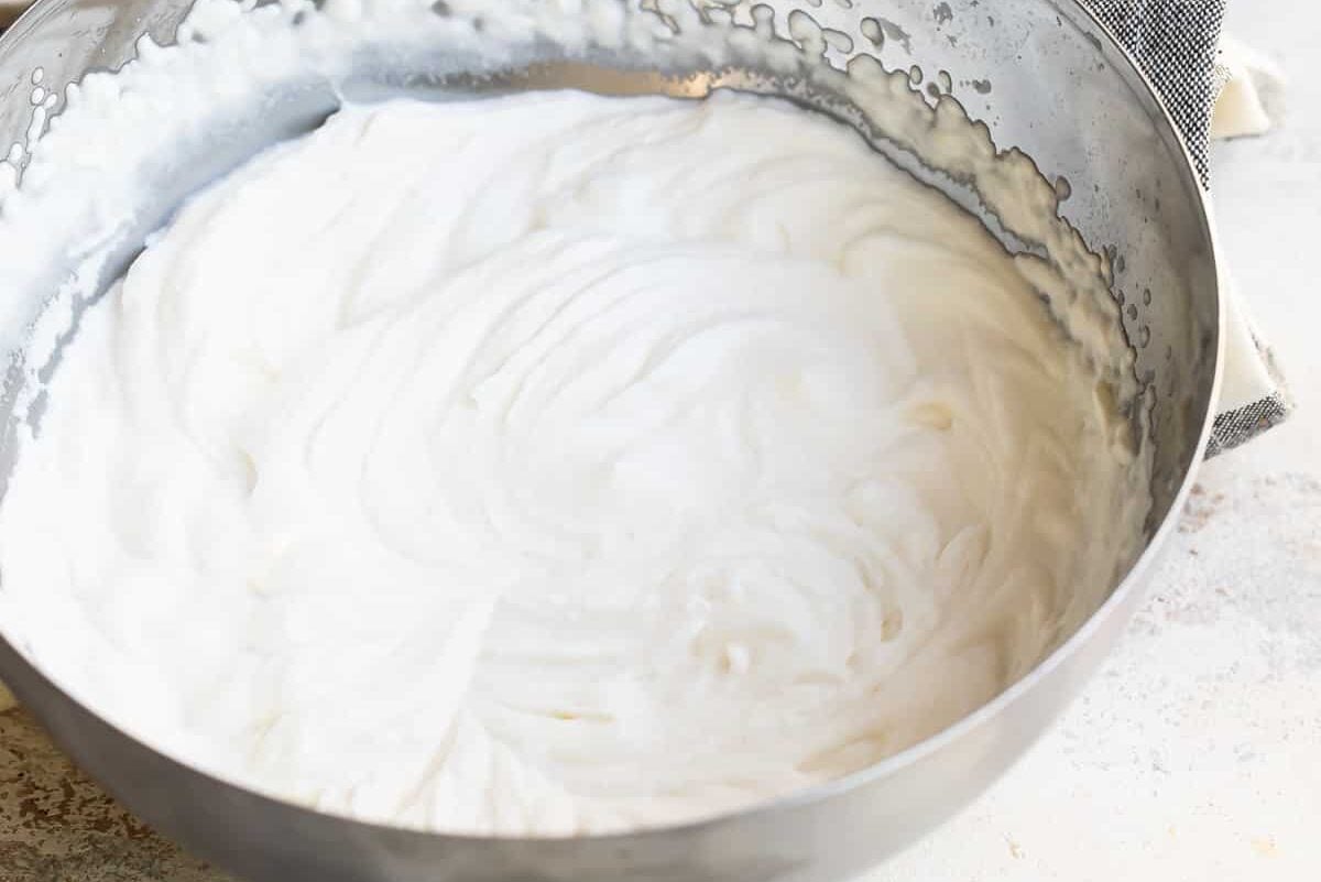 A metal mixing bowl filled with whipped cream.