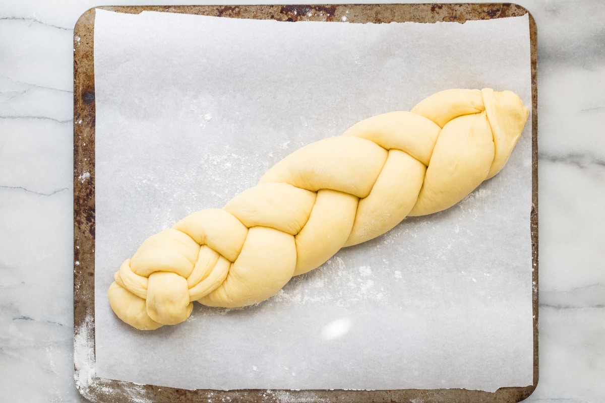 An overhead shot of a braided challah bread loaf on a baking sheet.