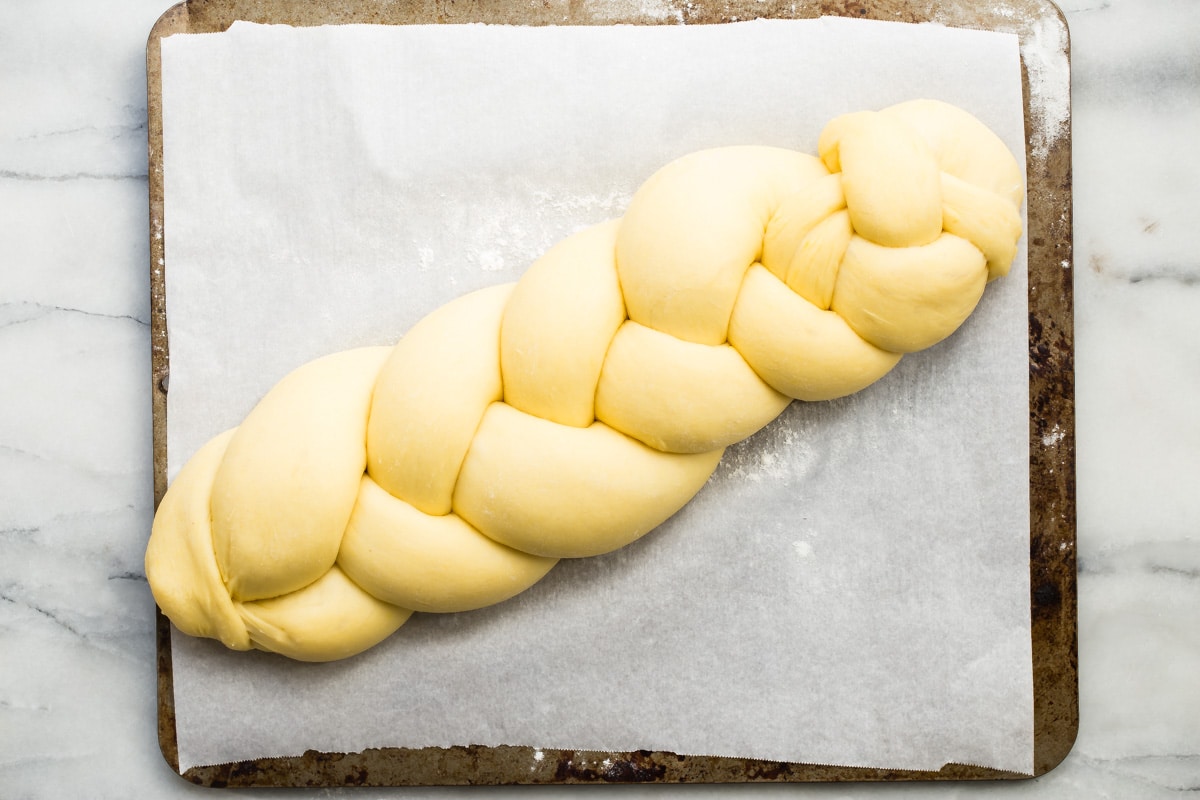 An overhead shot of a braided challah bread loaf on a baking sheet.