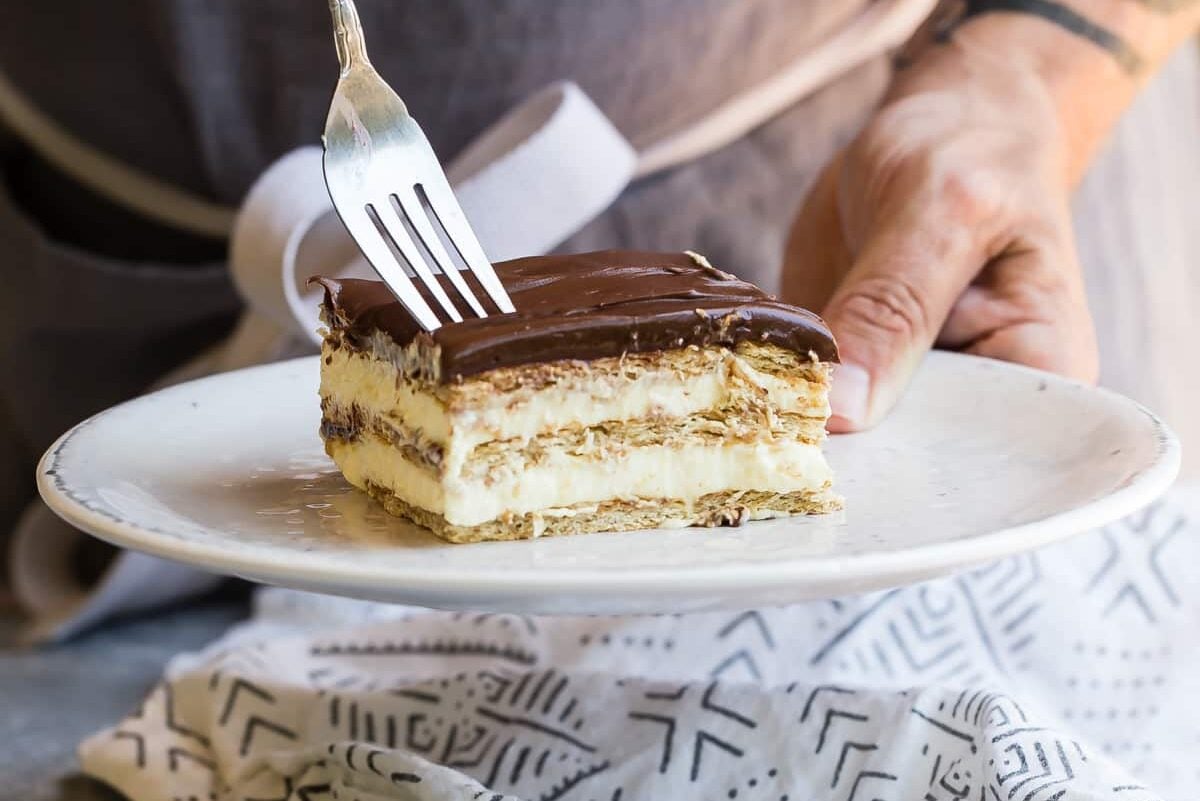 Someone sticking a fork into a slice of Chocolate Eclair Cake.