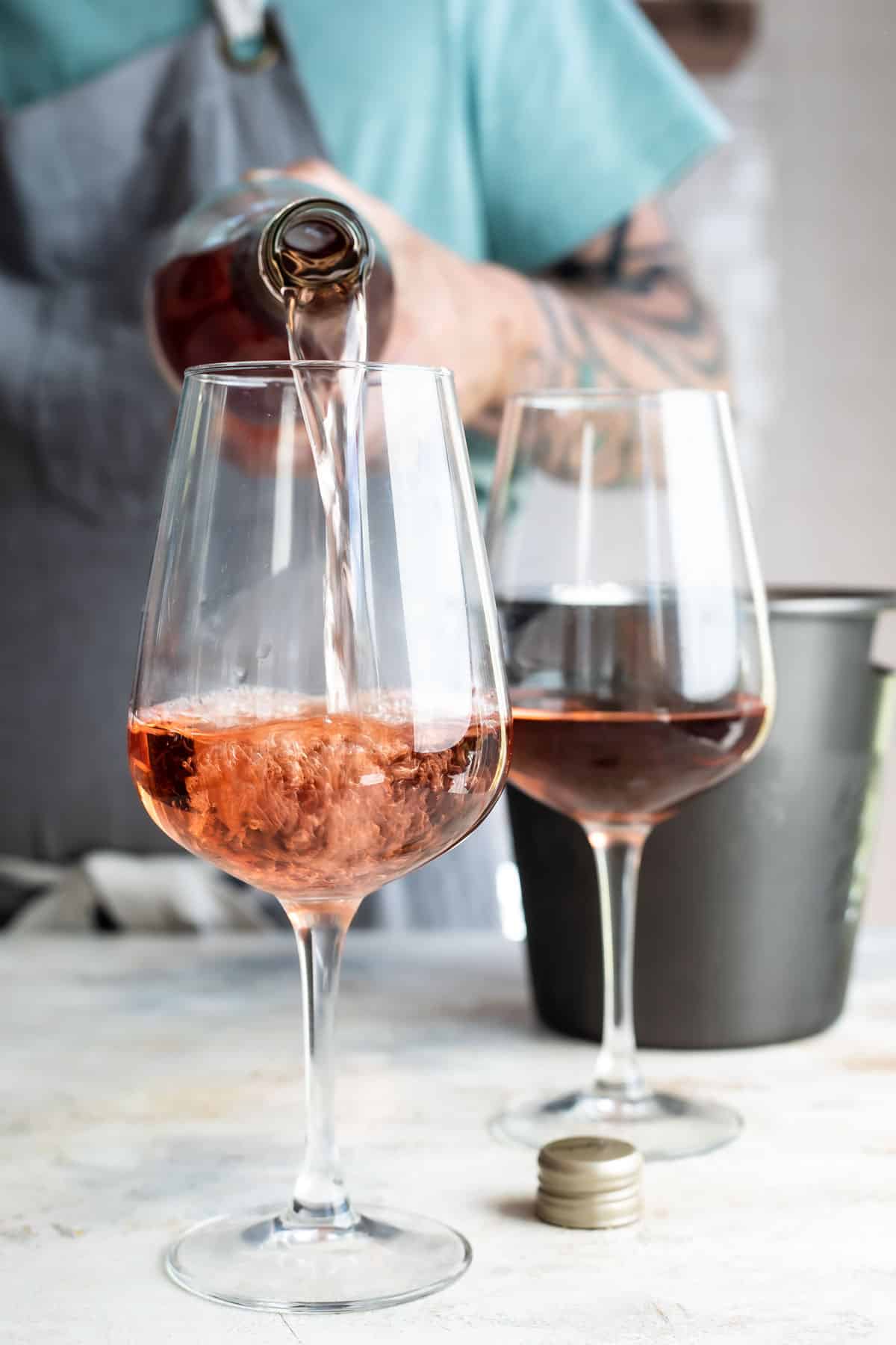 Somebody pouring two glasses of rose wine.