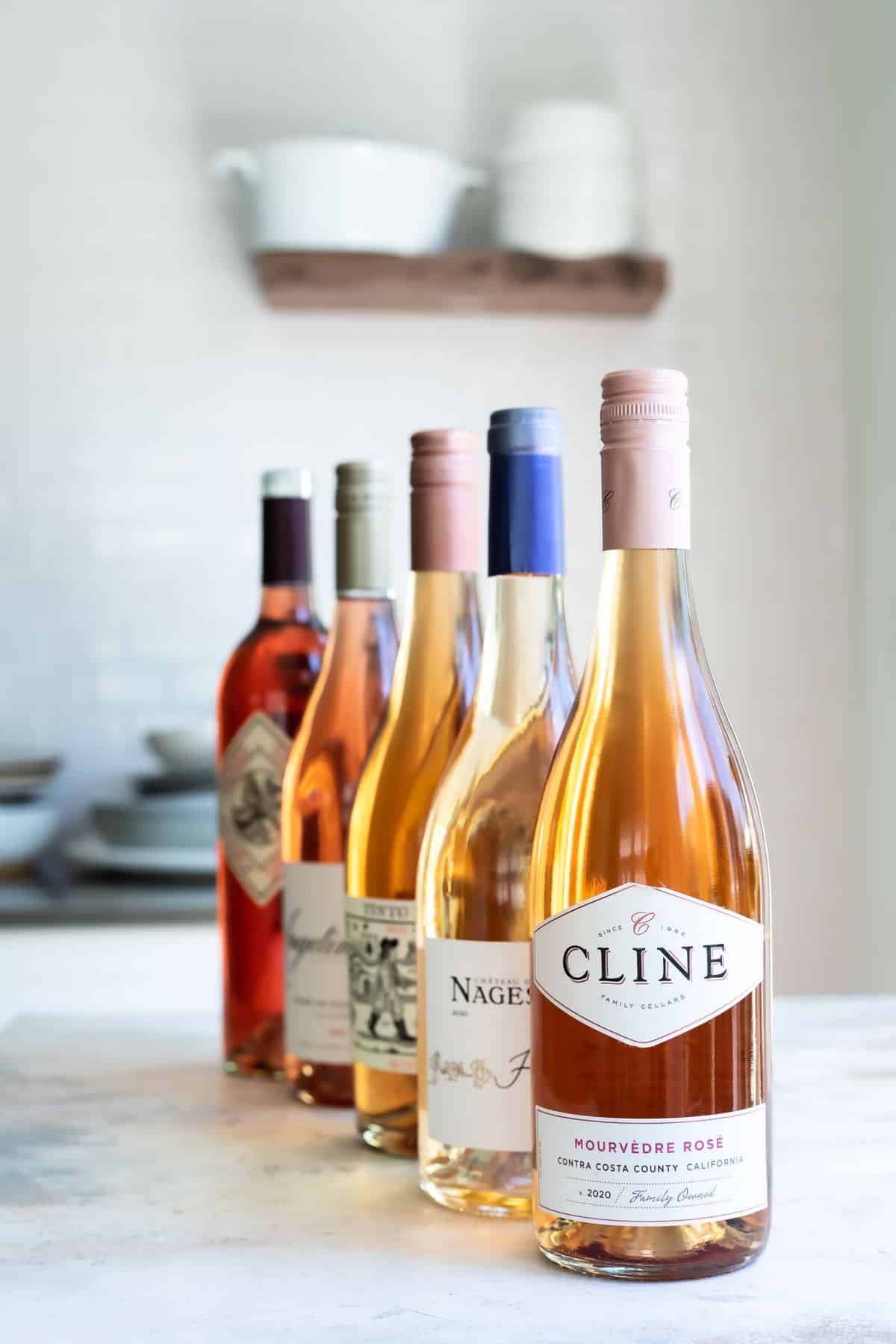 Several bottles of rose wine lined up next to each other.