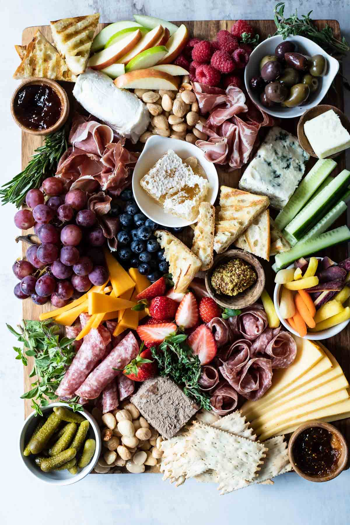 A charcuterie board filled with meats, cheese, fruits, nuts, crackers, and other snacks.