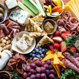 A charcuterie board filled with meats, cheese, fruits, nuts, crackers, and other snacks.