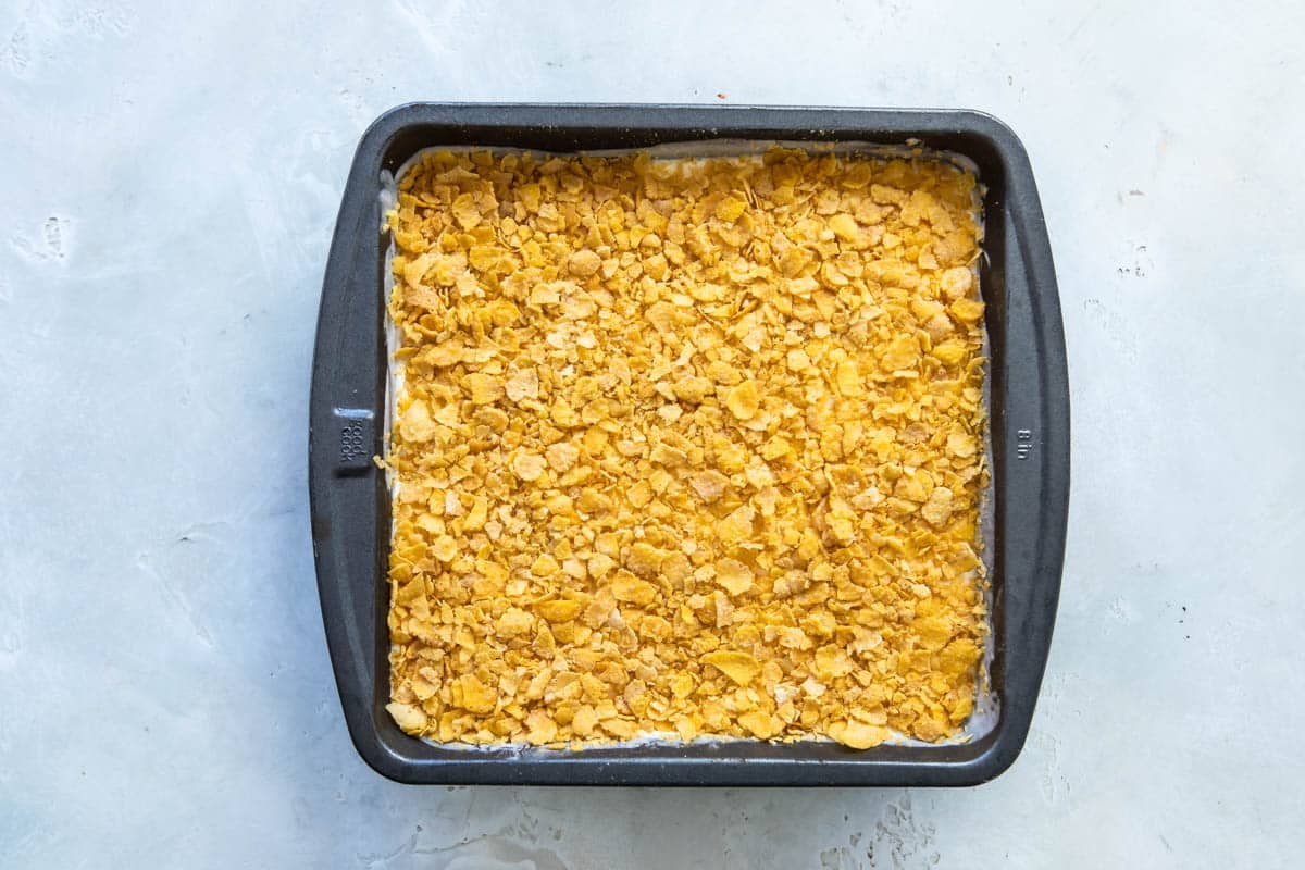 Ice cream with corn flakes on top in a square baking dish.