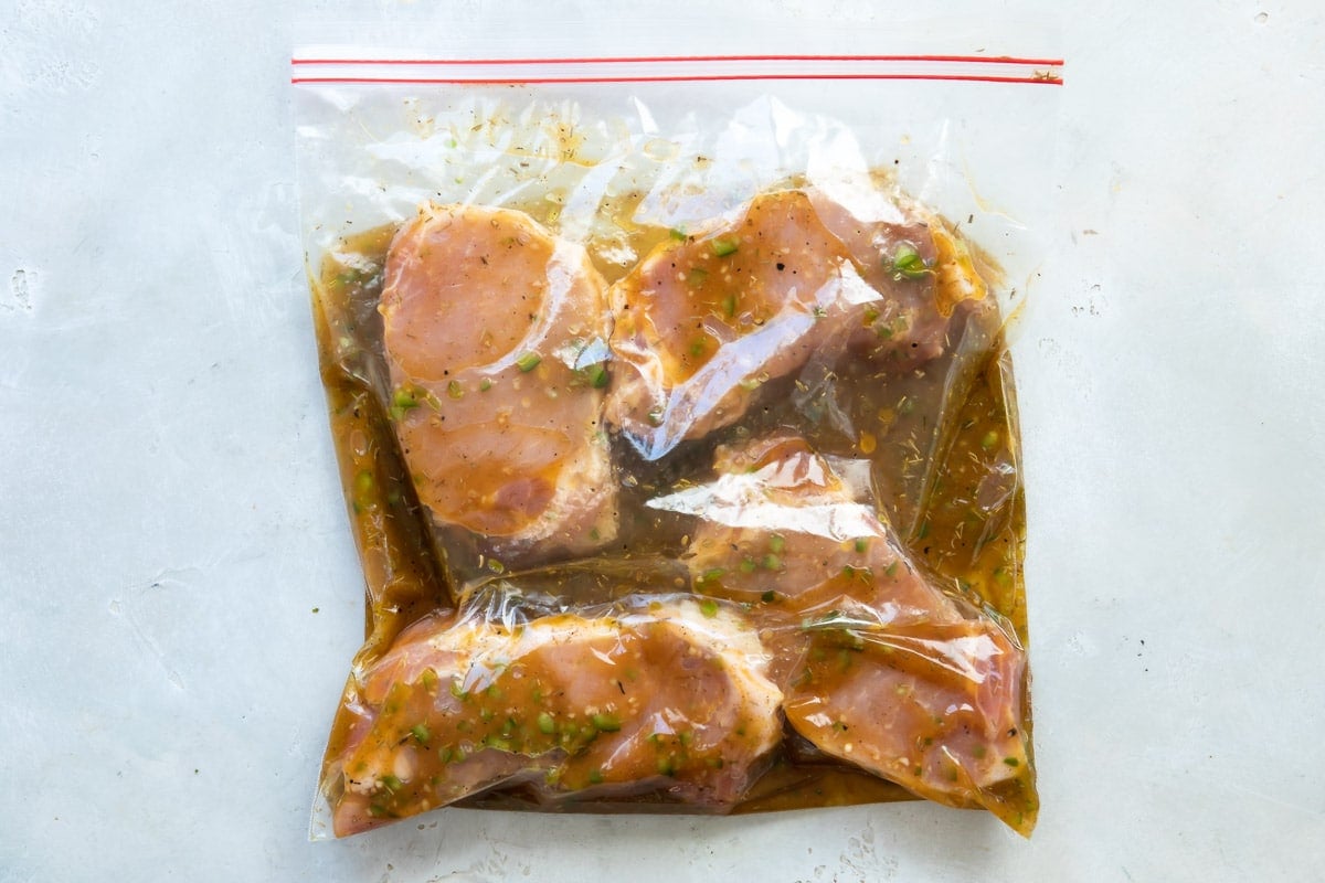 Raw pork chops in a plastic bag with marinade.