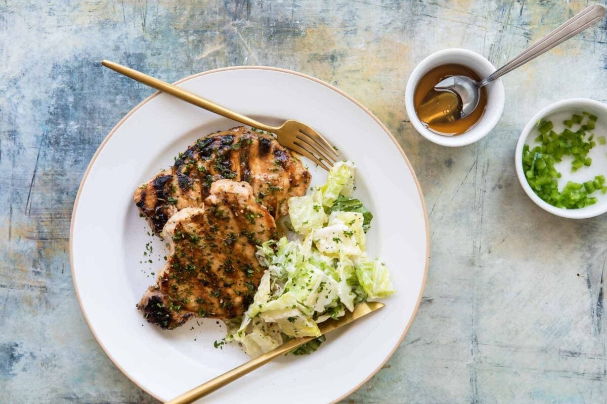 2 grilled pork chops plated with salad.