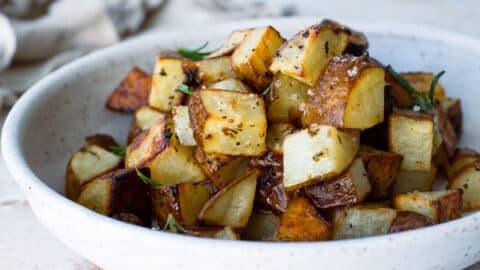Oven roasted potatoes in a white serving bowl.
