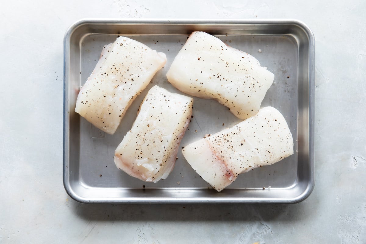 Raw halibut filets on a baking sheet.
