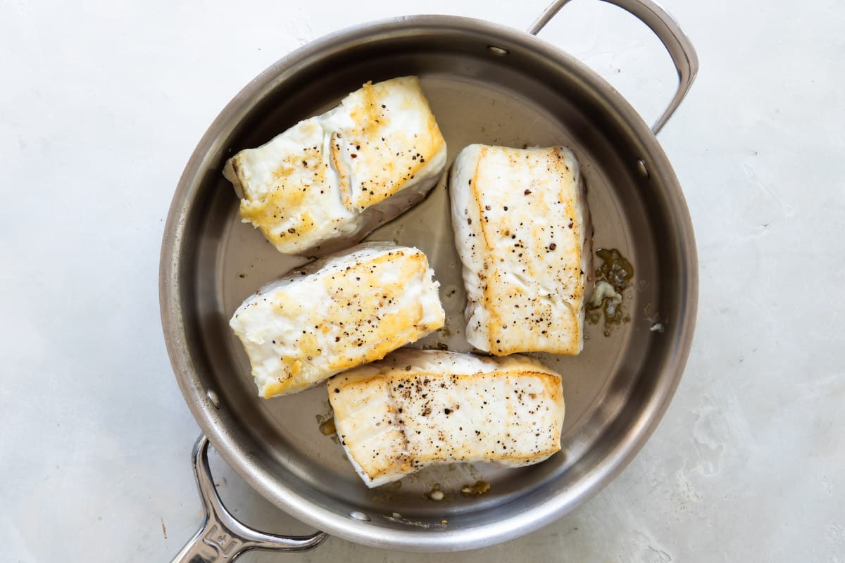 Seared halibut filets in a skillet.
