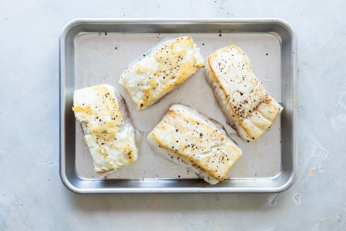 Seared halibut filets on a baking sheet.