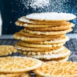 Pizzelle cookies being dusted with powdered sugar.