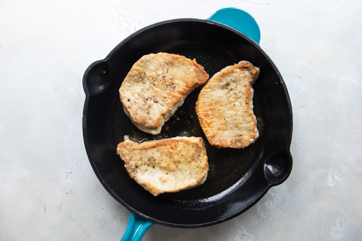 Pork cutlets in a cast iron skillet.