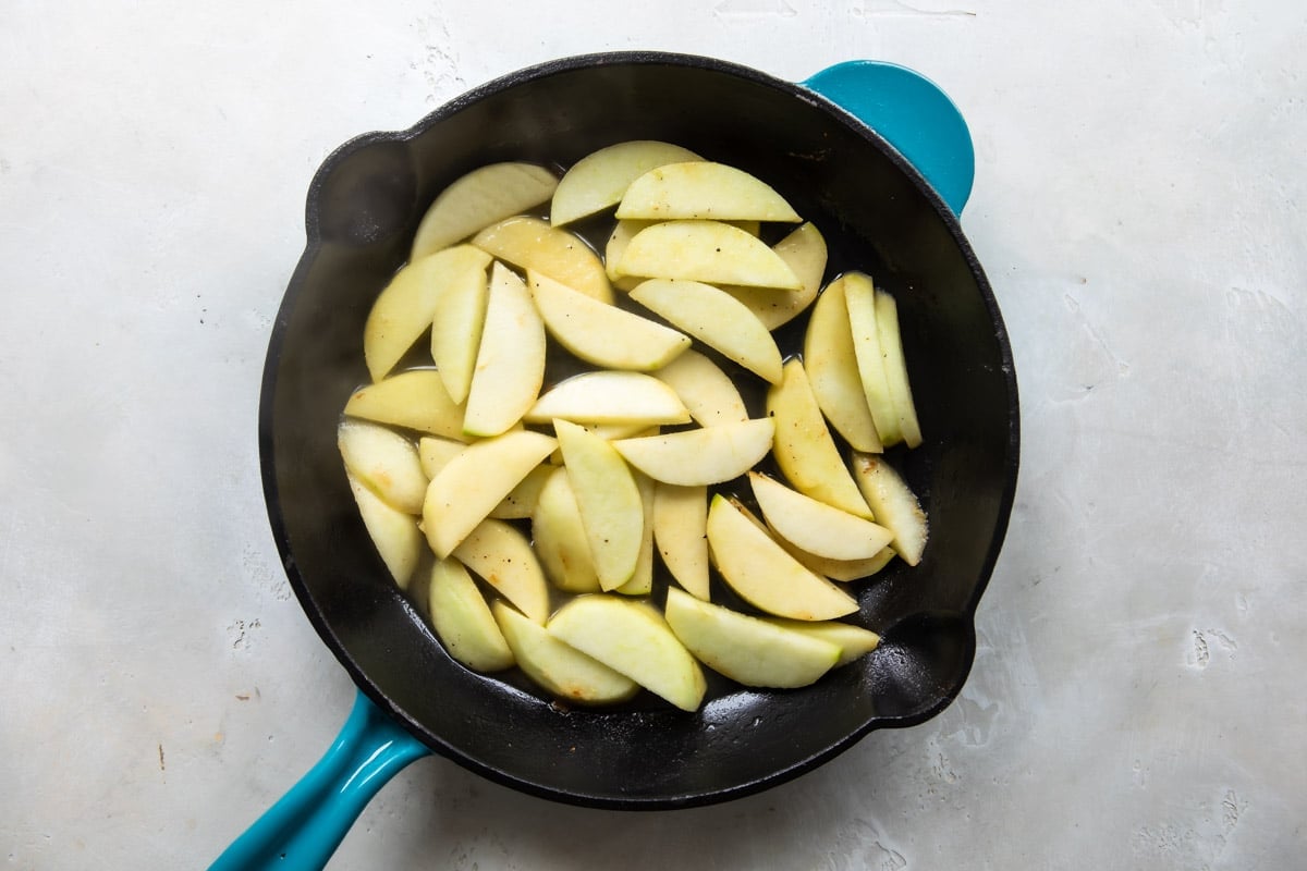 Sliced apples in a cast iron skillet.