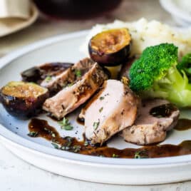 A plate with mashed potatoes, broccoli and pork tenderloin with figs.