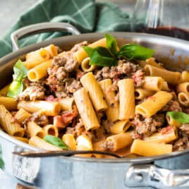 Rigatoni with sausage in a silver skillet.