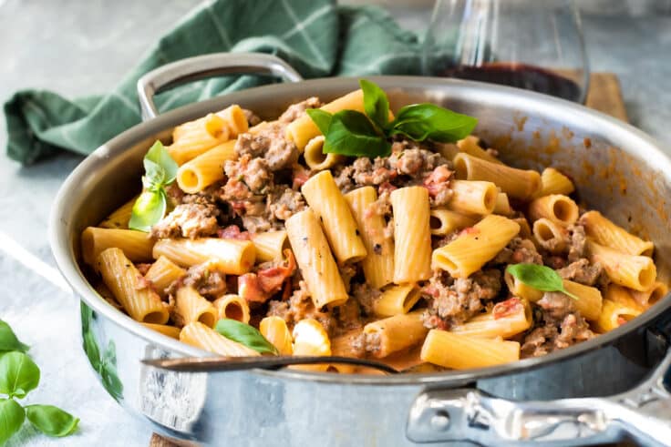 Rigatoni with sausage in a silver skillet.