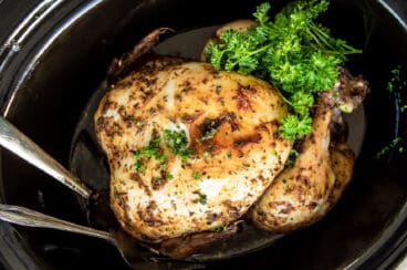 A rotisserie chicken in a black crock pot.