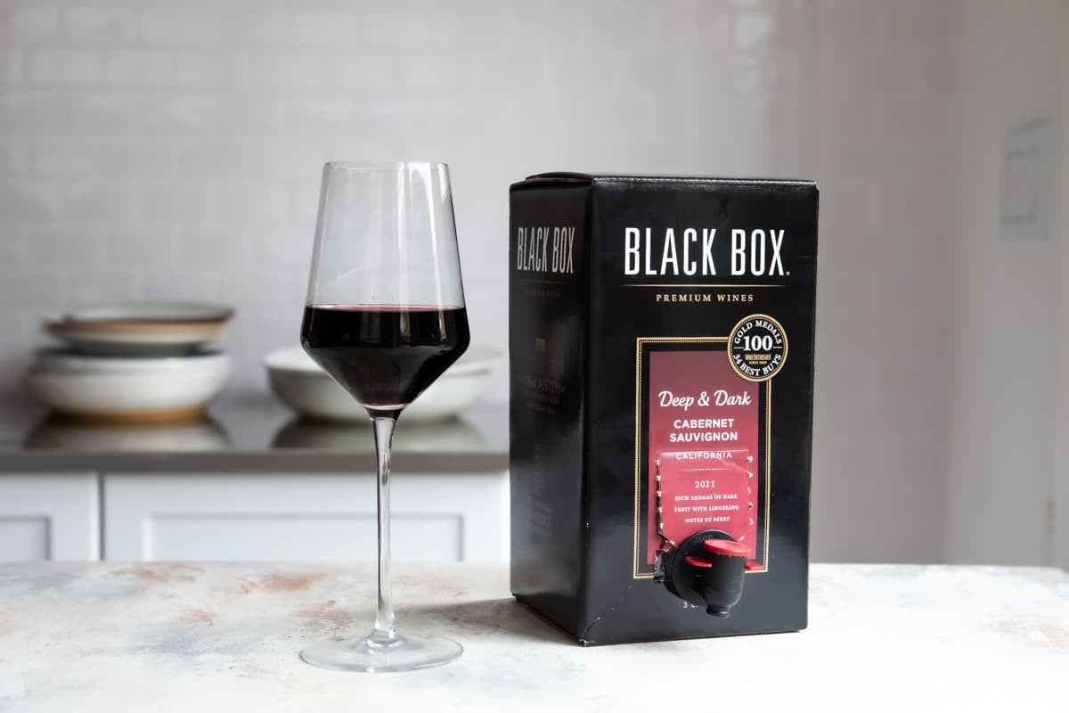 A box of cabernet sauvignon next to a wine glass.