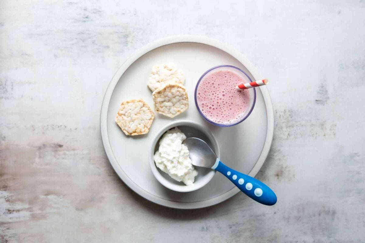 A plate with a smoothie, cottage cheese, and crackers on it.