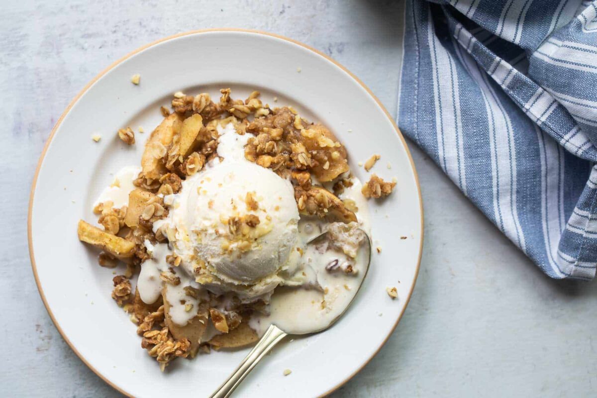 A plate of apple crisp topped with vanilla ice cream.