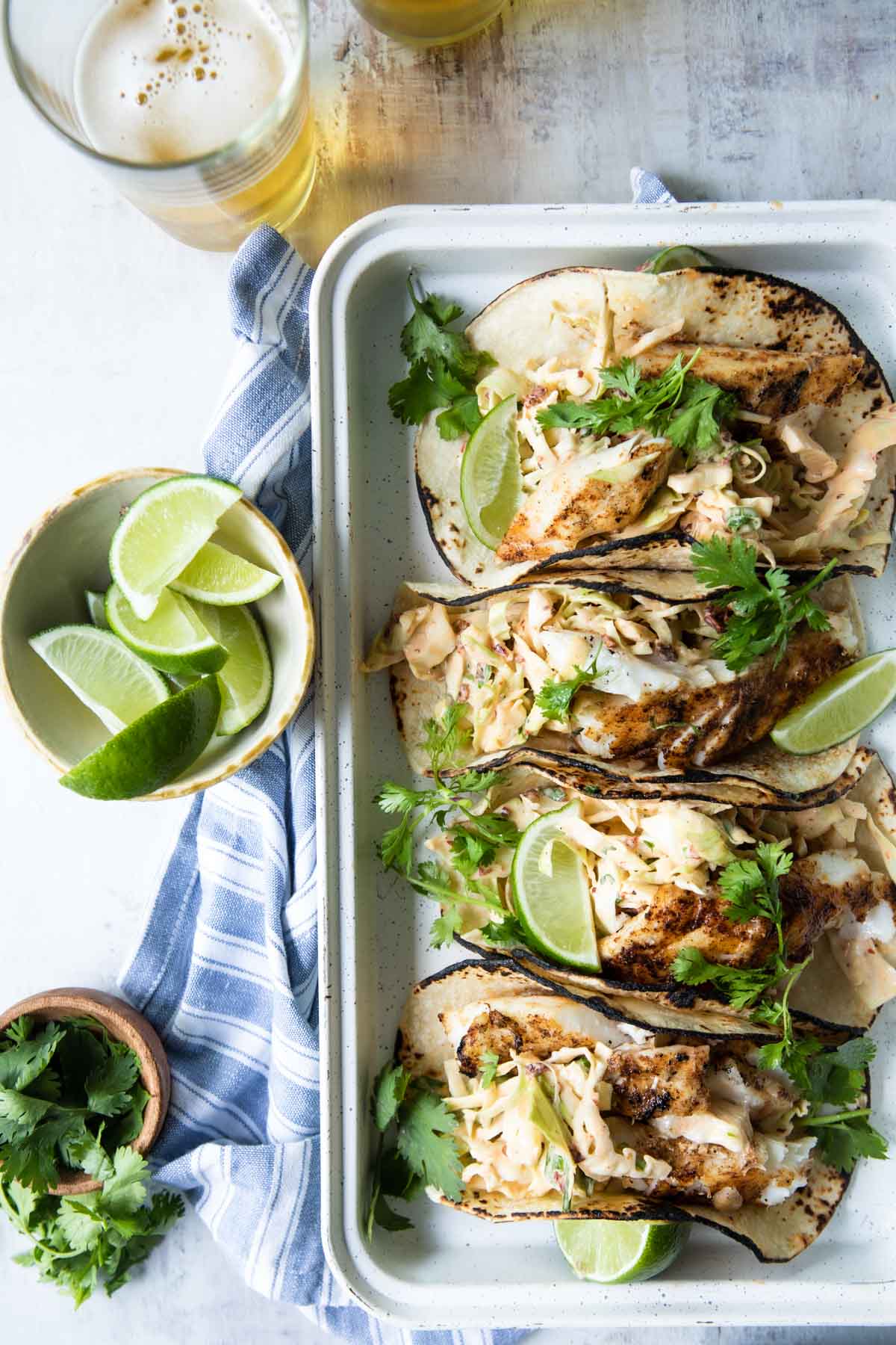 Four grilled fish tacos on a platter.