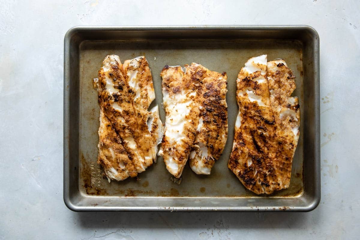 Fish on a baking sheet after being grilled.