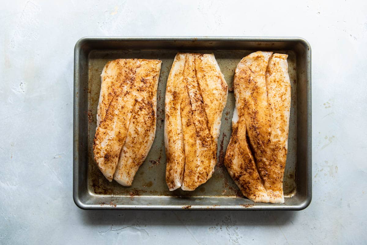 Seasoned fish on a baking pan.