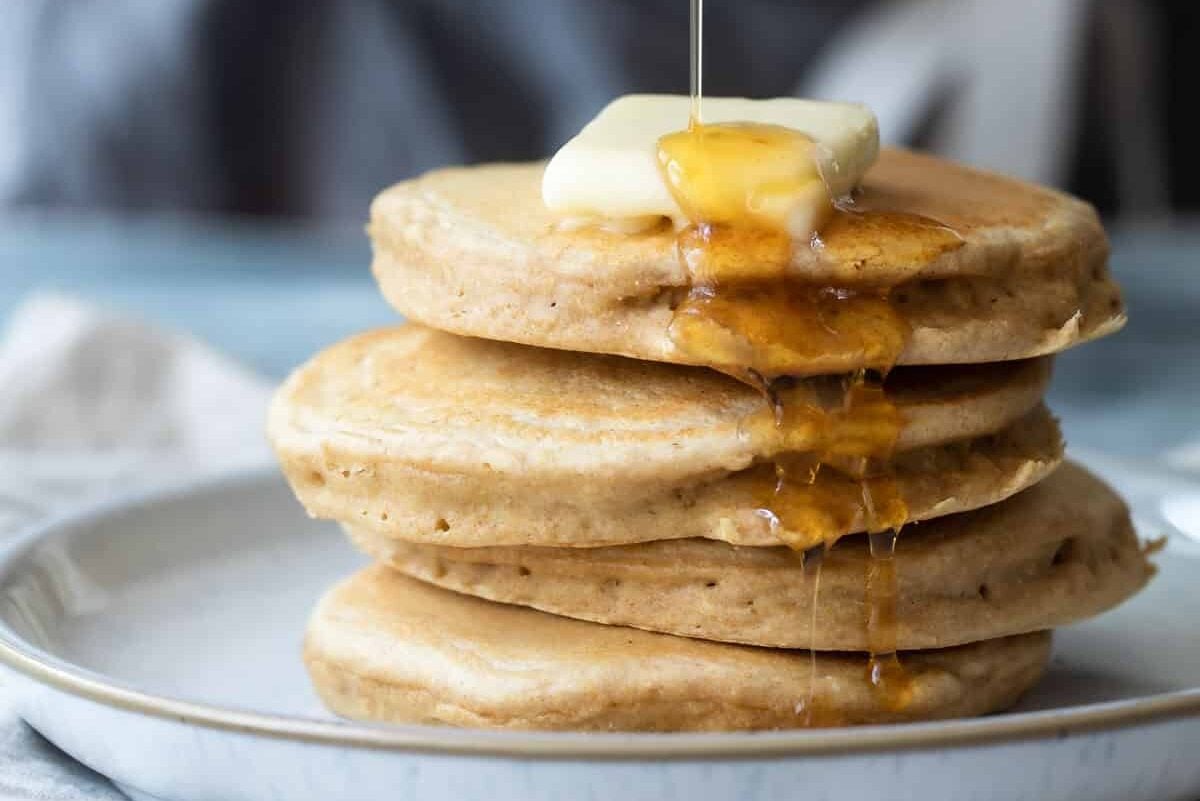 A stack of pancakes with butter and maple syrup.