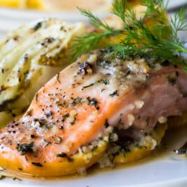 A baked salmon filet on a plate next to roasted fennel.