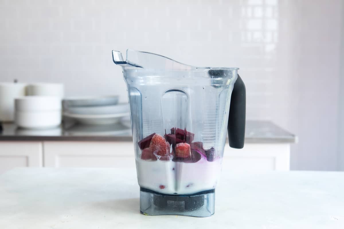 A blender filled with beet smoothie ingredients.