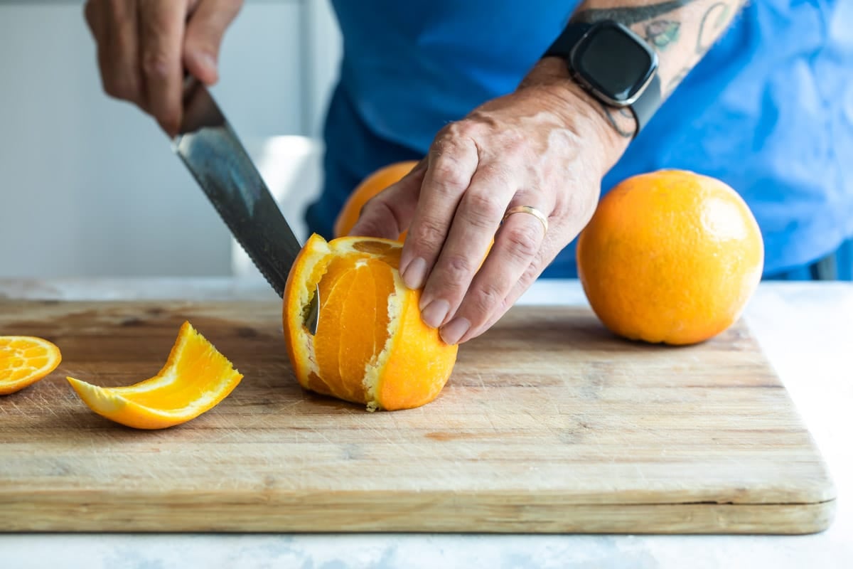 Peeling an orange on a cutting board.