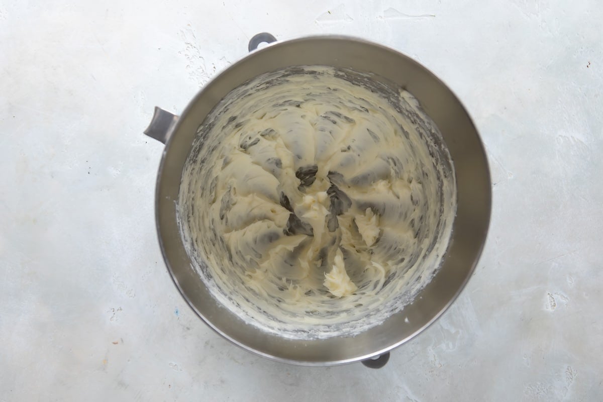 Butter and sugar being creamed in a silver mixing bowl.
