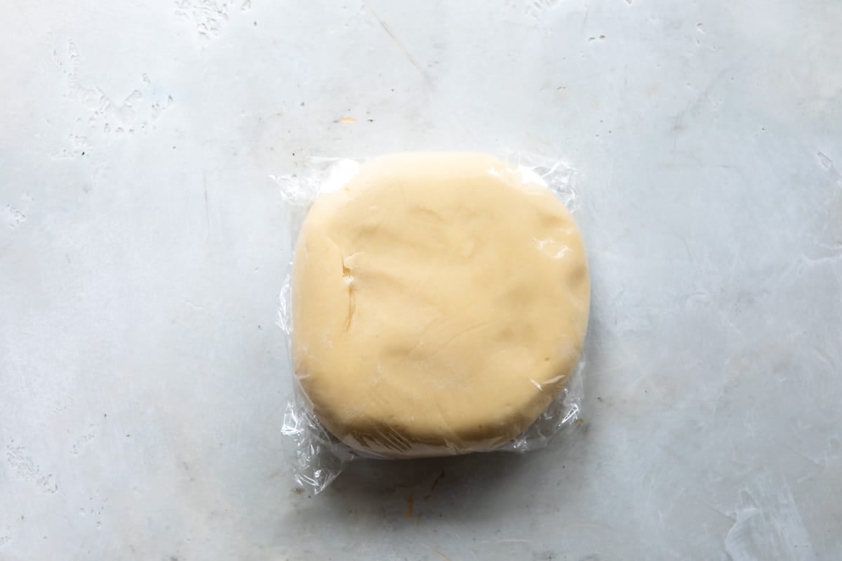 A ball of tart crust dough wrapped in plastic wrap.