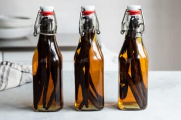 Three bottles of vanilla extract on a countertop.