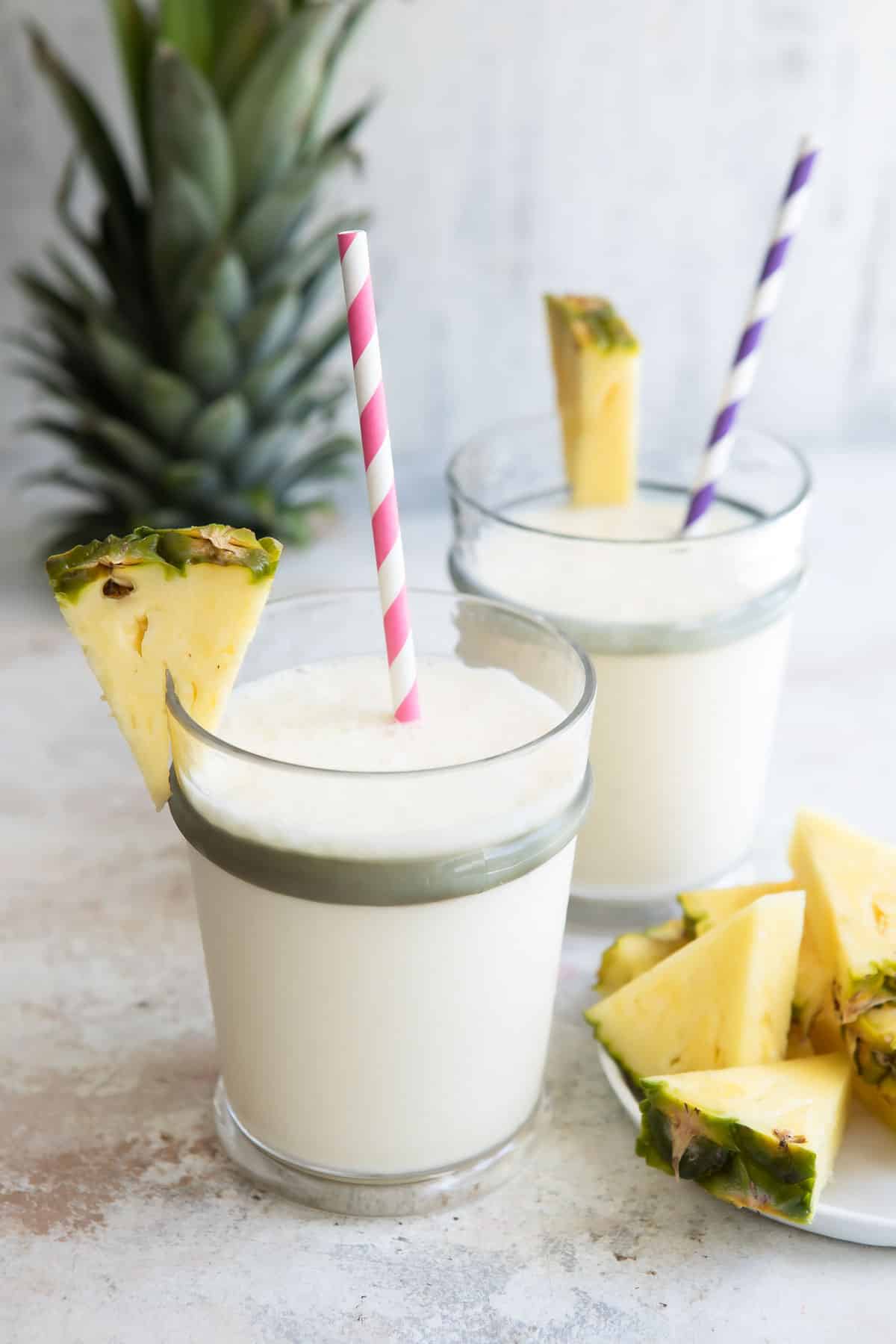 2 Pineapple Smoothies in glasses with striped straws.