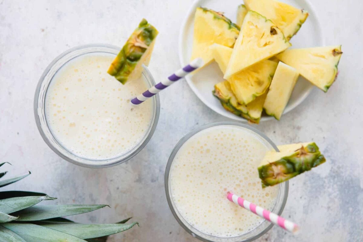 2 Pineapple Smoothies in glasses with striped straws.