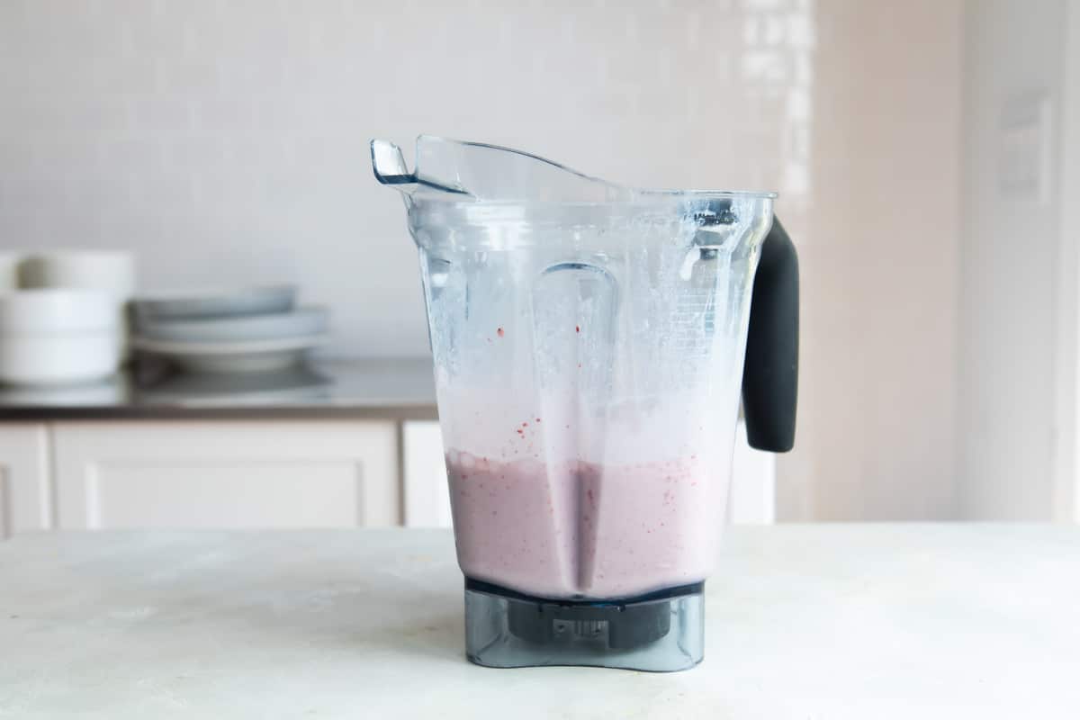 A blender with strawberry-banana smoothie ingredients inside.
