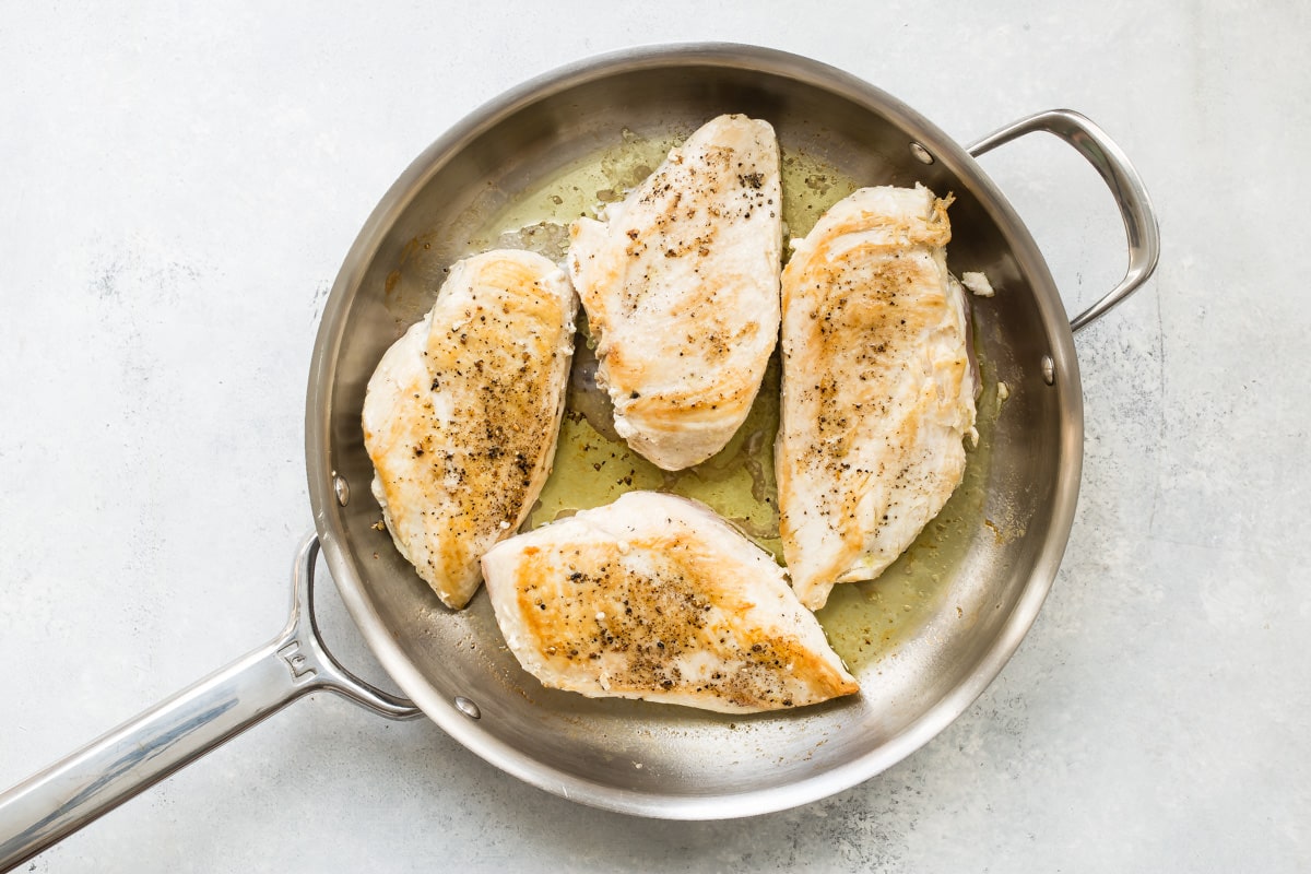 A skillet of poached chicken breasts.