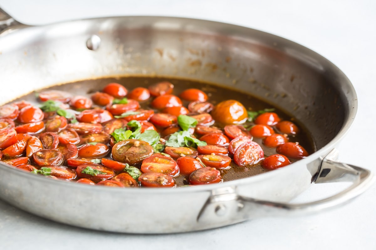 A skillet full of tomatoes and fresh basil in balsamic vinegar.