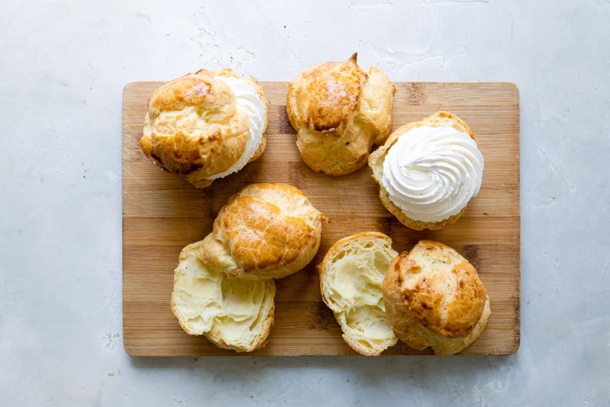 Split cream puffs, some with whipped cream inside, some not.