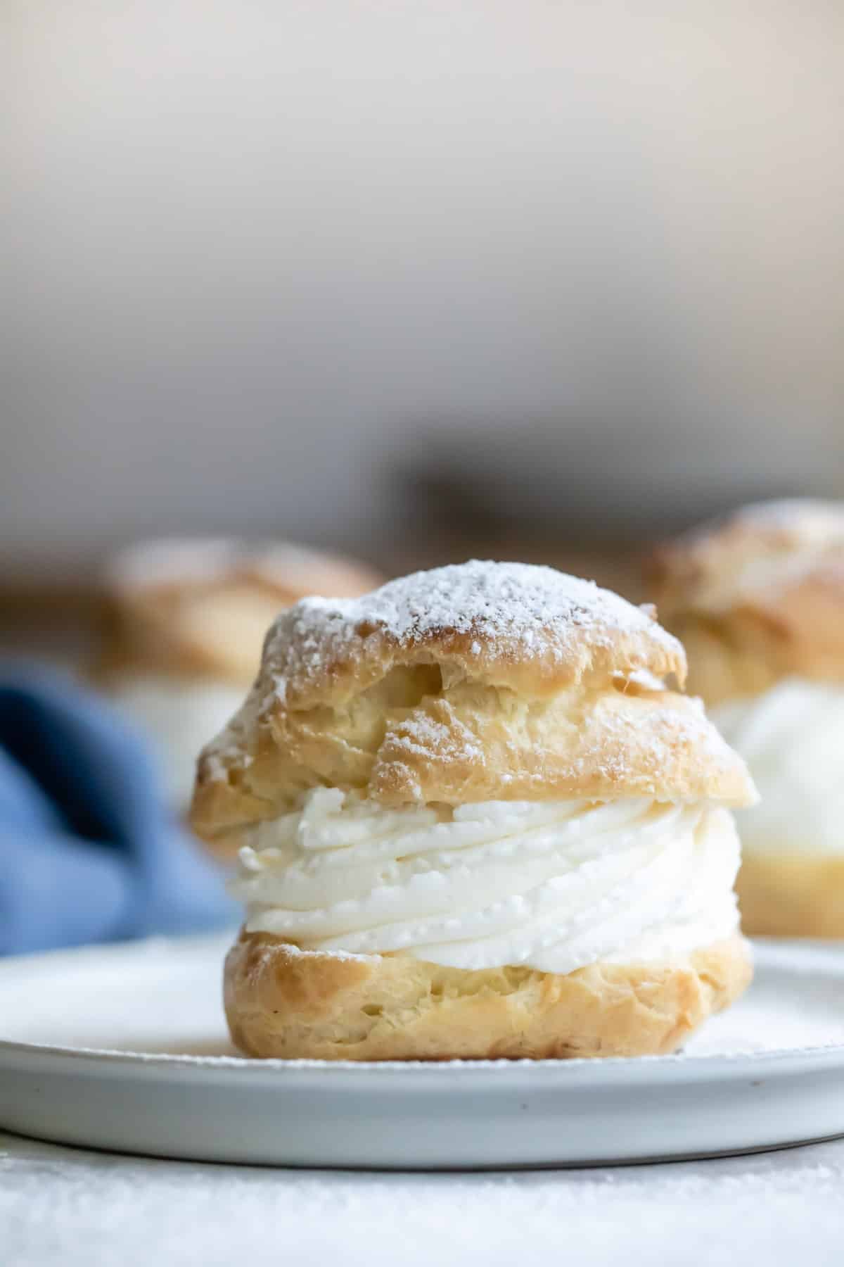 Dusting filled cream puffs with powdered sugar.