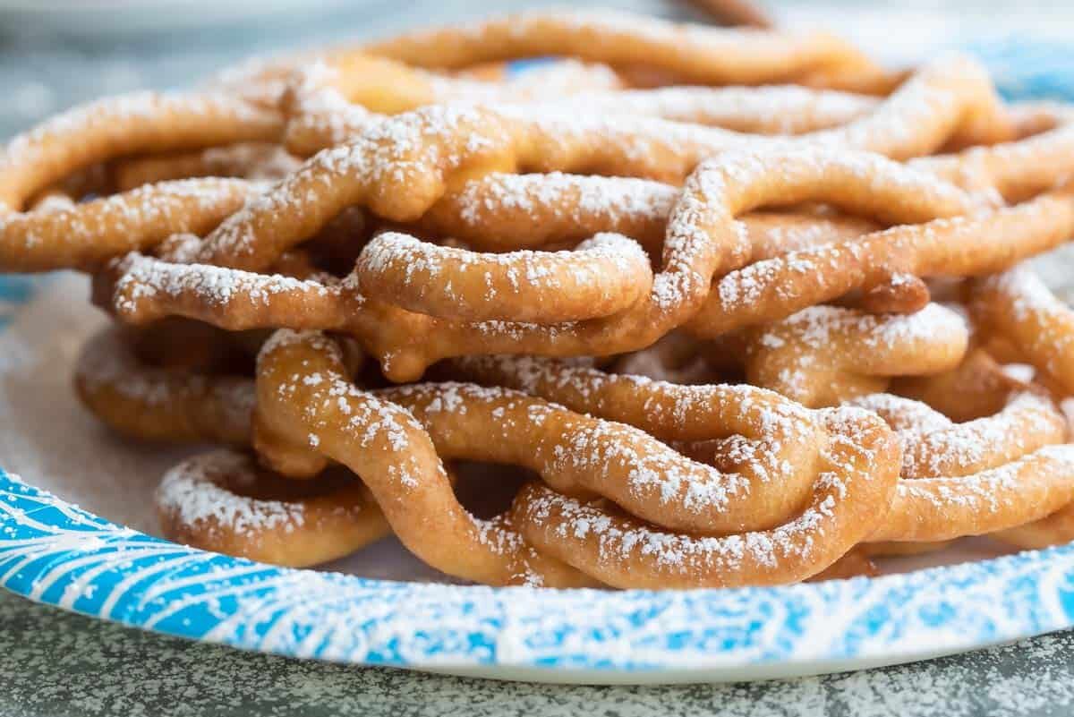 Paper plates with funnel cakes on top.