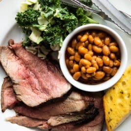 A plate of Santa Maria barbecue with tri-tip, salad, beans, and garlic toast.