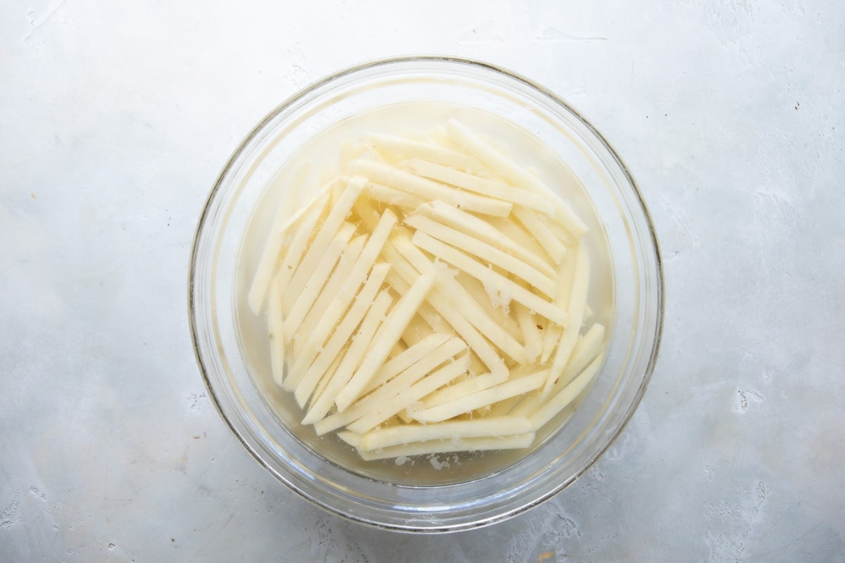 Cut french fries soaking in a bowl of water.