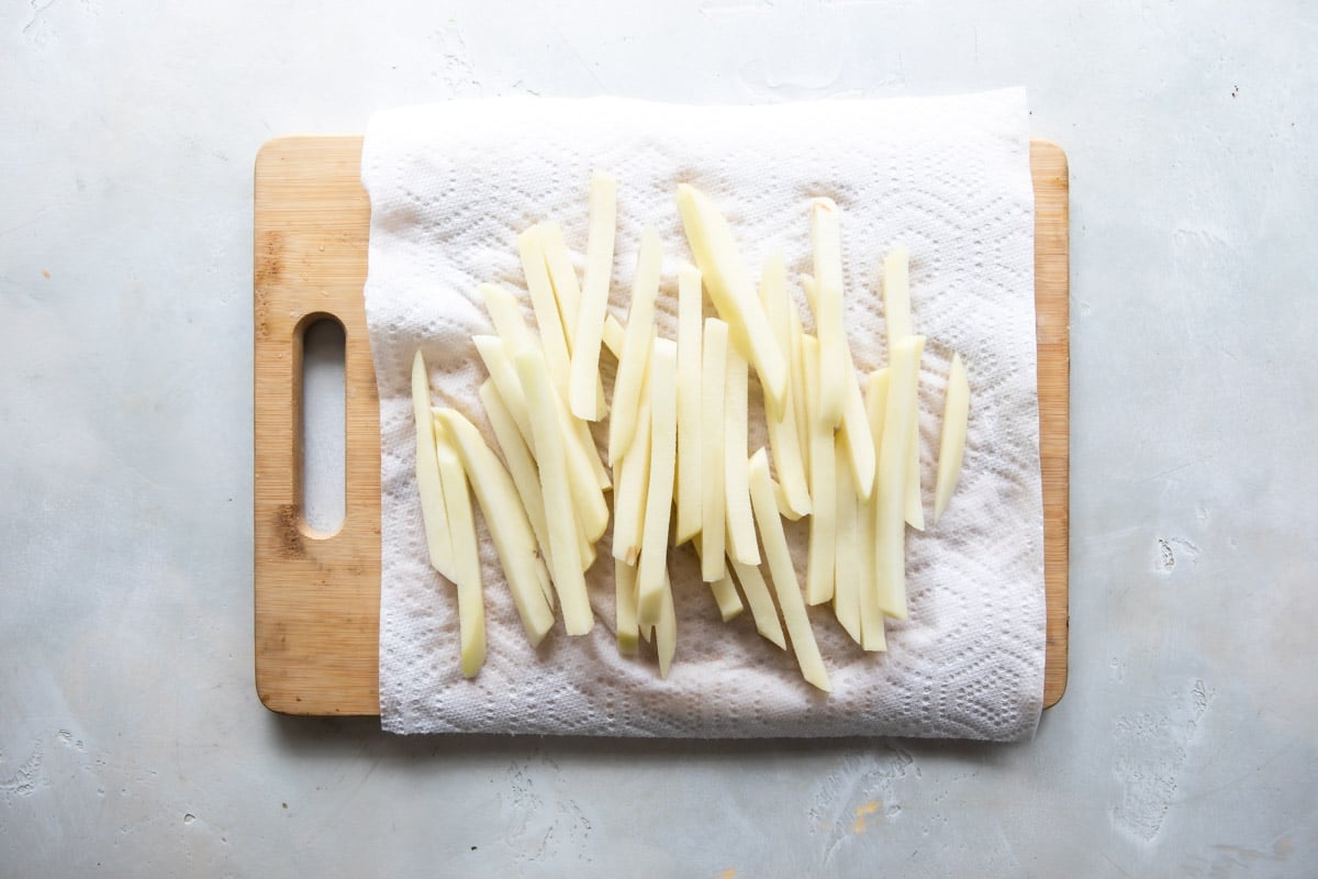 Cut french fries draining on paper towels.